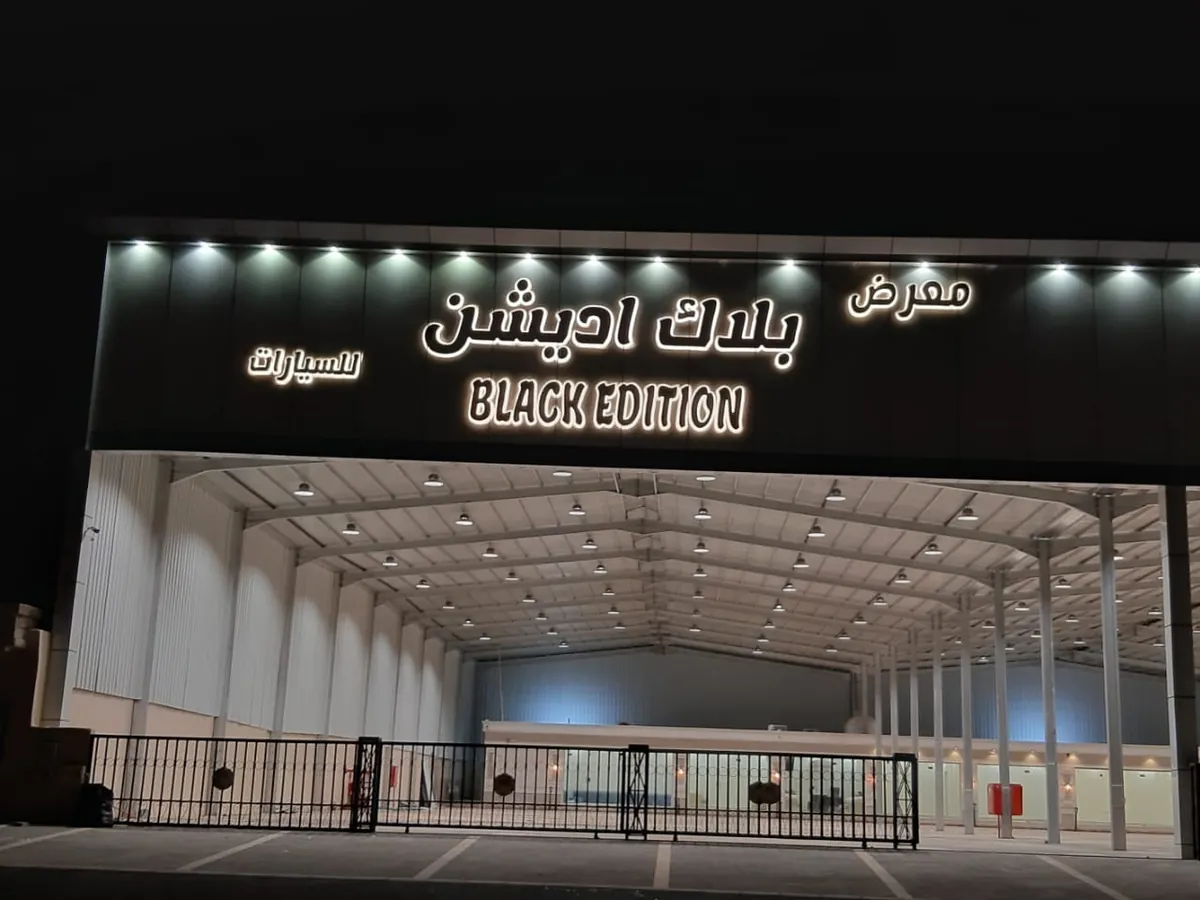 واجهة معرض بلاك اديشن للسيارات بأحرف بارزة مضيئة وكشافات فوق مدخل الهنجر
