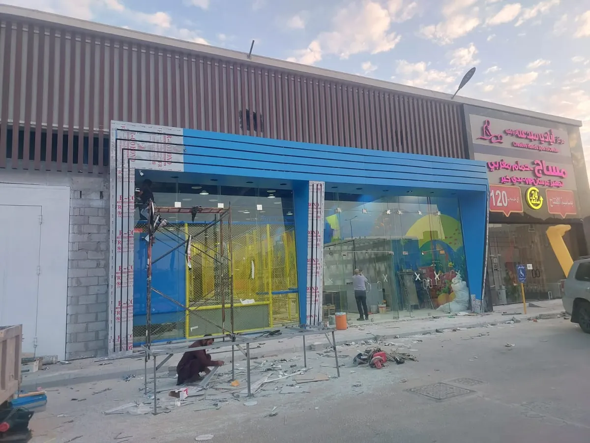 واجهة مركز ترفيهي بألواح كلادينج زرقاء حول واجهة زجاجية أثناء التنفيذ