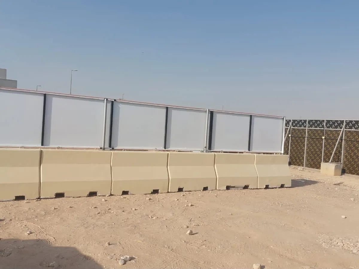 سور ألواح بيضاء مثبتة فوق حواجز خرسانية حول أرض مشروع