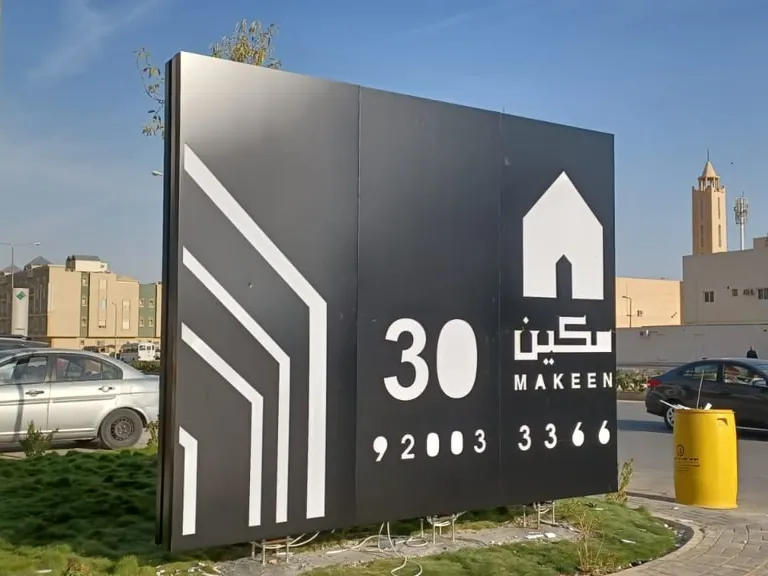 لوحة مشروع مكين 30 بألواح سوداء وشعار وأرقام بيضاء بجانب الطريق