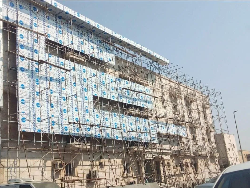 مبنى قائم من عدة طوابق تحيط به السقالات أثناء تركيب ألواح الكلادينج على واجهته
