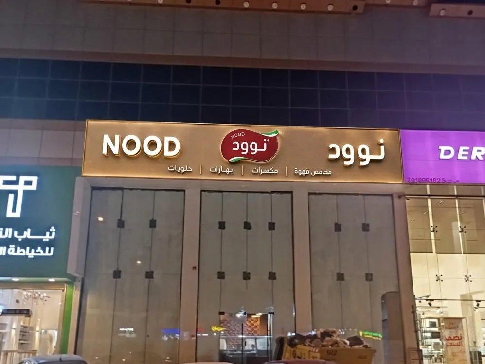 لوحات محلات تجارية متجاورة منها لوحة نوود بأحرف بارزة عربية وإنجليزية